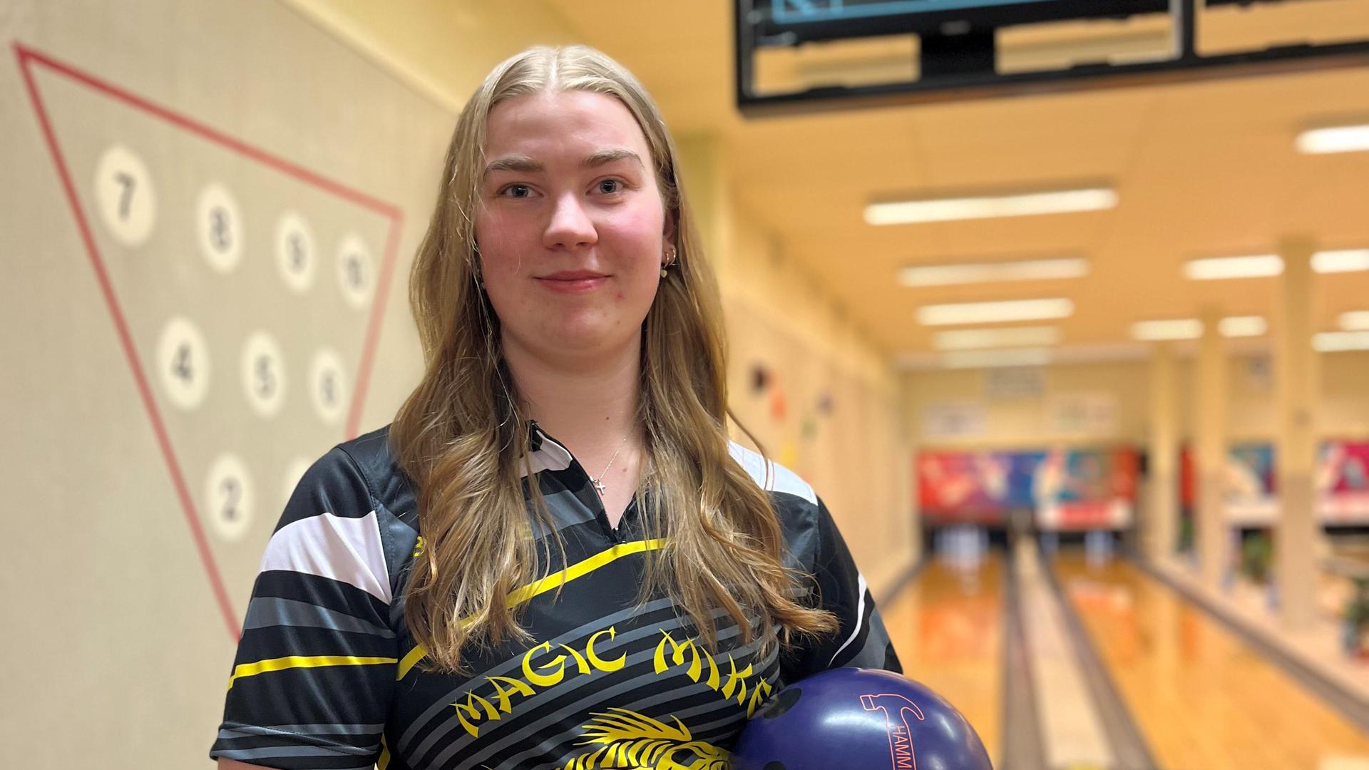 En kvinna står med ett bowlingklot i famnen